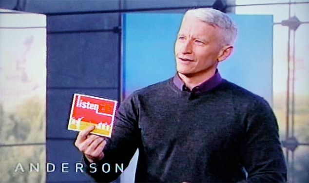 Anderson Cooper holding Our Time's Benefit Album, Listen, on his daytime talk show.